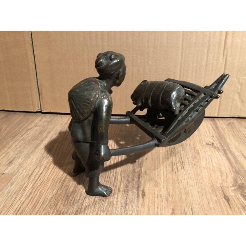 Sculpture of an Asian character pushing a wheelbarrow with her vintage pig, 1900