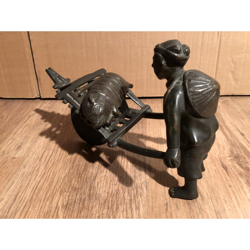 Sculpture of an Asian character pushing a wheelbarrow with her vintage pig, 1900
