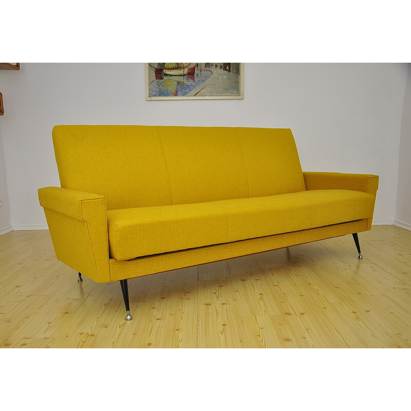 Sofá cama vintage amarillo sobre patas de metal, años 70