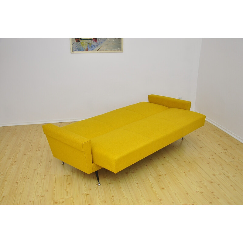 Sofá cama vintage amarillo sobre patas de metal, años 70