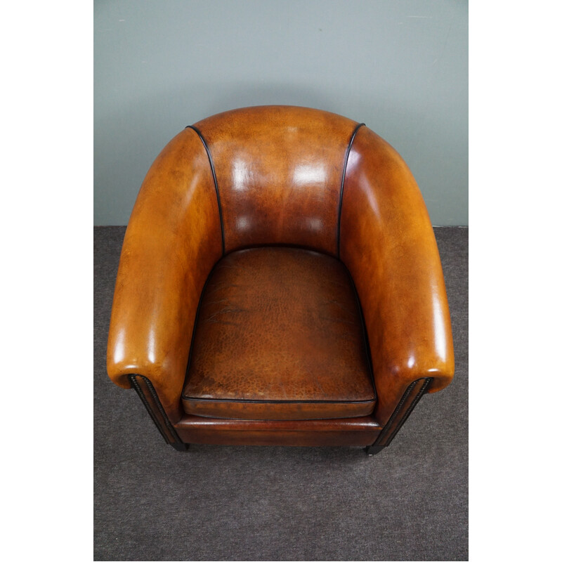 Vintage club chair in sheepskin with black piping and decorative studs